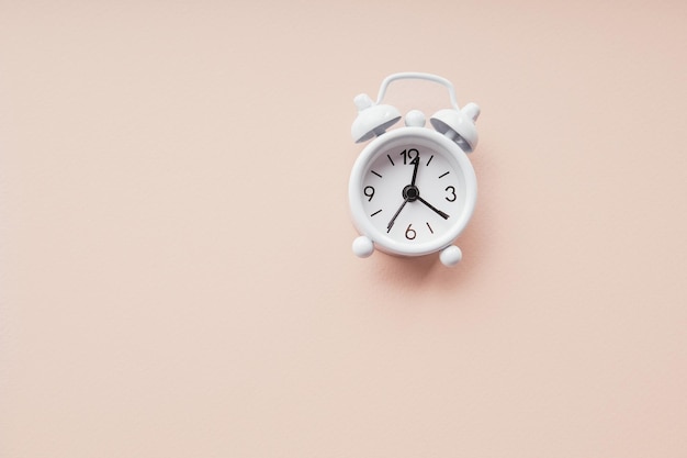 Despertador branco isolado em um fundo de papel rosa Conceito de prazo