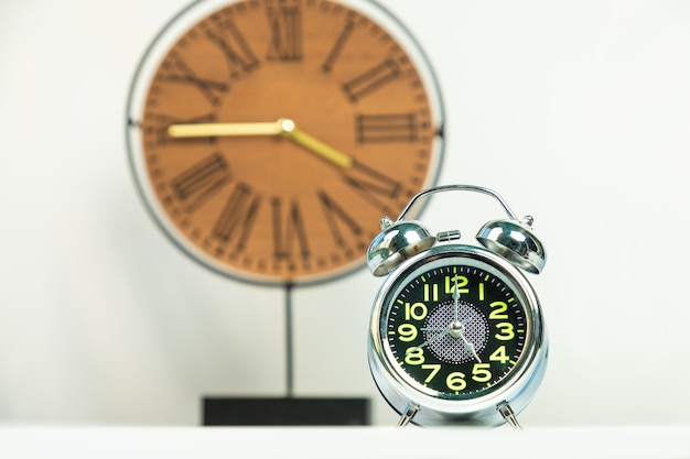 Foto despertador brilhante com fundo de relógio de madeira isolado no branco