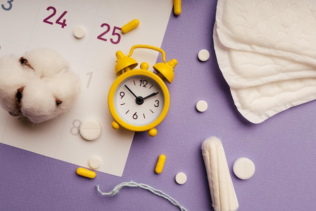 Despertador en el calendario con toallas sanitarias menstruales y cierre de tampones Concepto médico de días críticos para la mujer y menstruación