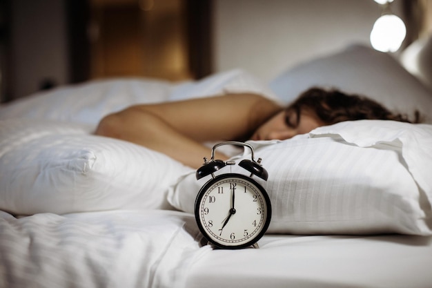 Despertador en la cama con mujer dormida detr s Foto Premium