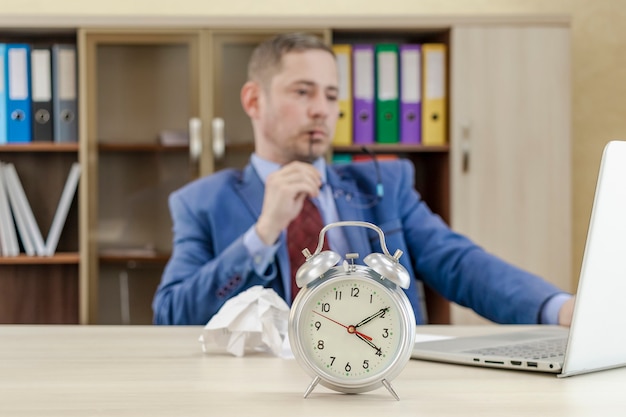 Despertador clássico em uma mesa de escritório com papel amassado o chefe roe seus óculos