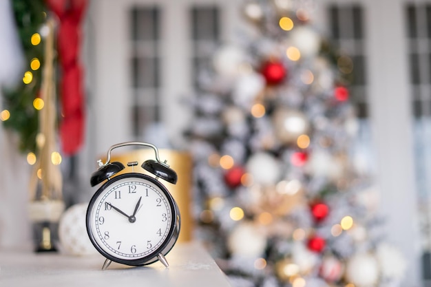 Despertador de Natal na mesa branca com luzes acesas. . Foto de alta qualidade