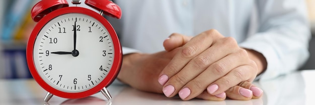 Despertador en el escritorio con mujer de negocios o concepto de tiempo temprano en la mañana o tarde en la noche