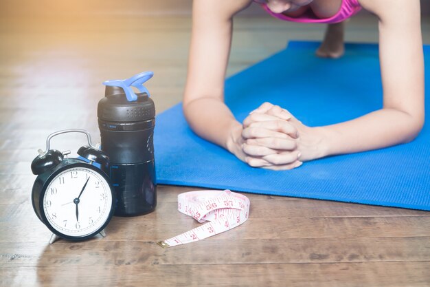 Despertador, fita métrica e mulher yoga asiática em casa, fundo de trabalho e conceito de estilo de vida, foco seletivo