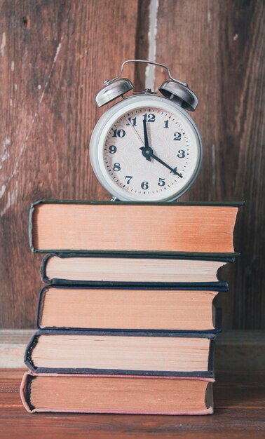 Despertador y libros sobre una mesa de madera