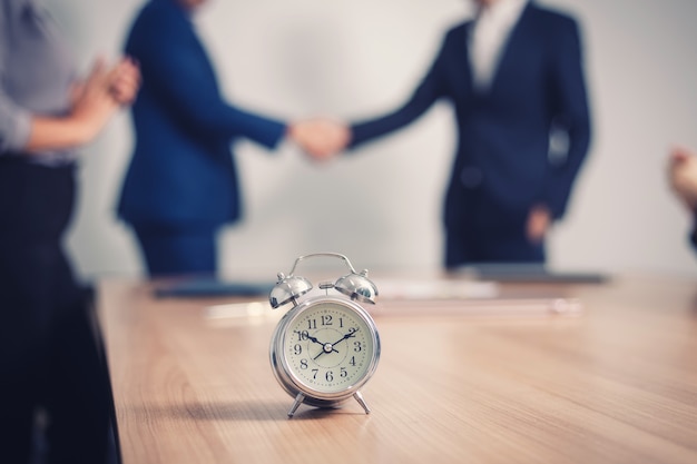 Despertador en mesa con gente de negocios en la sala de seminarios.