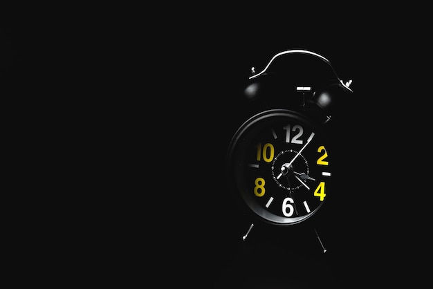 Despertador moderno redondo negro sobre fondo negro con espacio de copia El concepto de insomnio y ansiedad nocturna