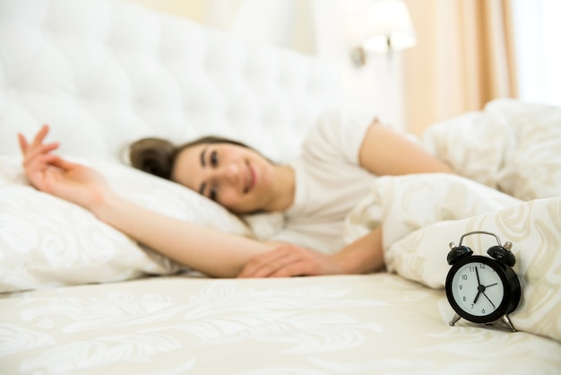 Despertador na mesa e mulher dormindo