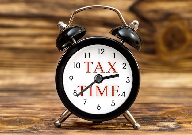 Despertador con palabras TAX TIME en el fondo de madera Concepto de negocio