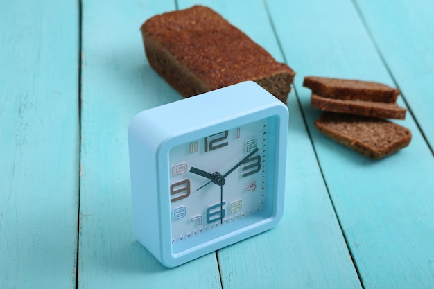 Despertador con pan de centeno de grano entero en rodajas sobre fondo de madera azul