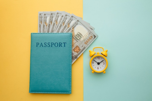 Despertador y pasaporte con billetes de dinero en colores.