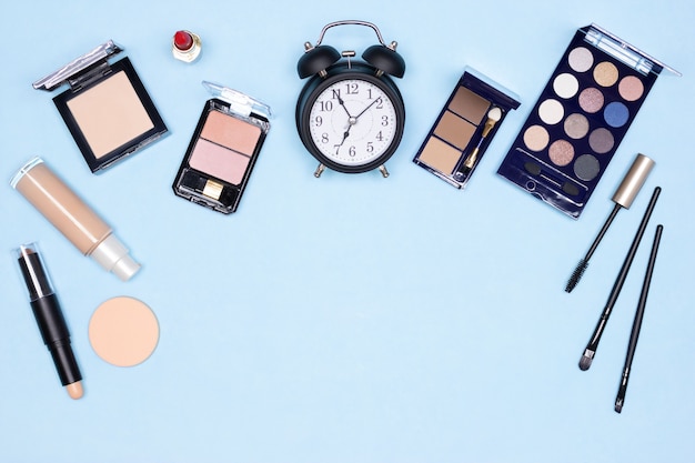 Despertador con productos de maquillaje esenciales Concepto de maquillaje rápido de cinco minutos con espacio de copia