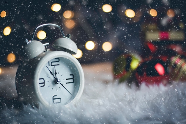 Foto despertador retro de navidad decorado con caja de regalo y abeto festivo en el fondo bokeh borrosa