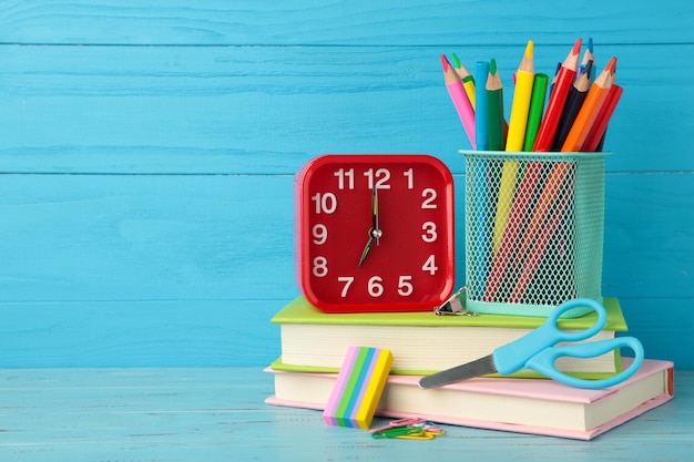 Foto despertador rojo y accesorios escolares sobre un fondo azul concepto de regreso a la escuela