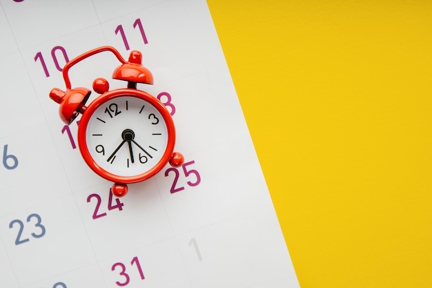 Despertador rojo y calendario sobre un fondo amarillo primer plano Concepto de fecha límite
