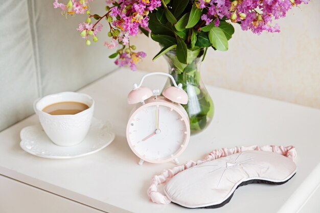 Despertador, taza de café y ramo de flores rosas