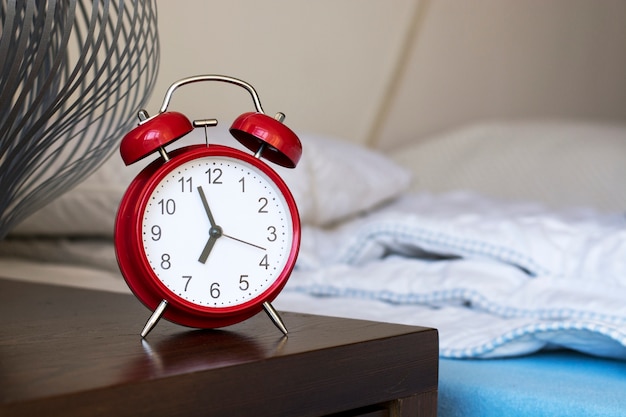 Foto despertador vermelho ao lado da cama