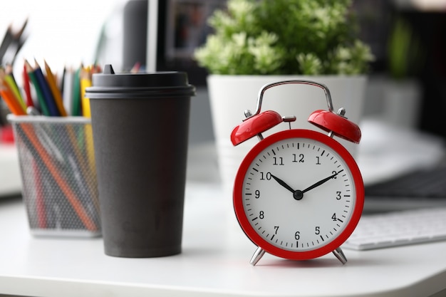 Despertador vermelho com copo de café de papel preto