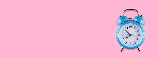 Foto despertador vintage azul sobre fundo de cor rosa claro