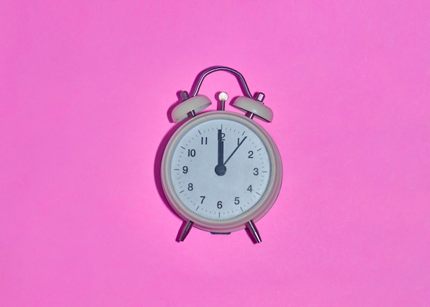 Despertador vintage sobre fondo rosa claro