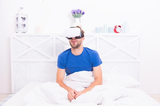 Despertar consciente. Retorne à realidade. Homem explorar VR enquanto relaxa na cama. Tecnologia VR e futuro. Comunicação VR. Impressões emocionantes. Despertar da realidade virtual. Espaço aumentado para jogos.