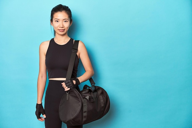 Desportista asiática segurando mochila de ginástica em estúdio
