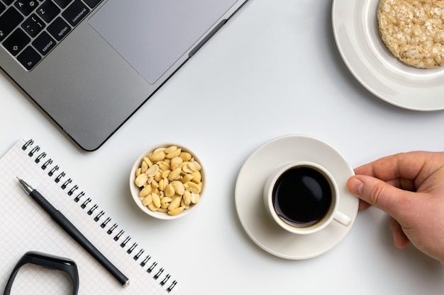 Desportista comendo arroz crocante rodadas com amendoim, xícara de café perto do laptop