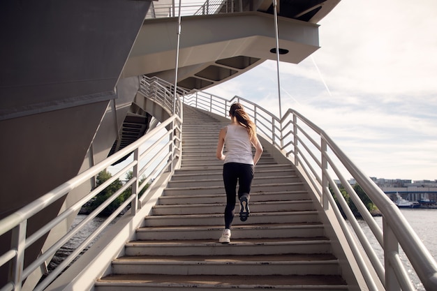 Desportista correndo na escada da ponte