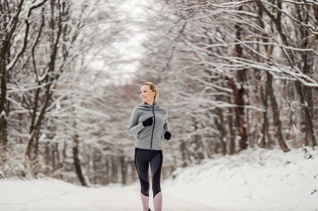 Desportista correndo na floresta em dia de inverno nevado. Esporte de inverno, fitness ao ar livre, vida saudável