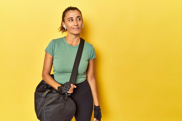 Foto desportista de meia-idade com mochila de ginástica em pano de fundo amarelo