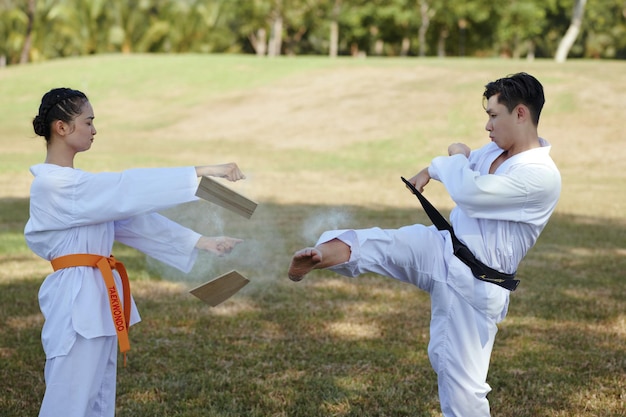 Desportista de taekwondo quebrando uma prancha de madeira