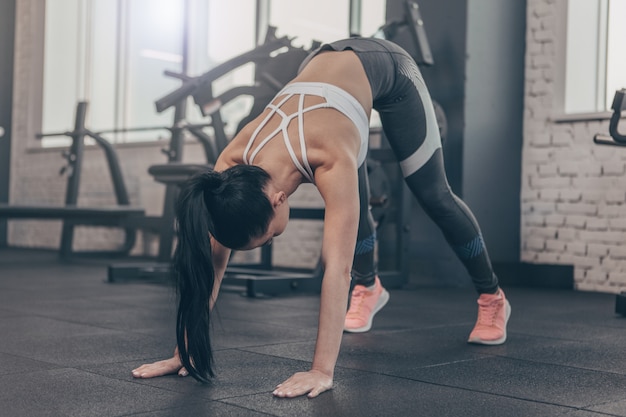 Desportista em forma de cabelos escuros, esticando o corpo antes do treino na academia, copie o espaço