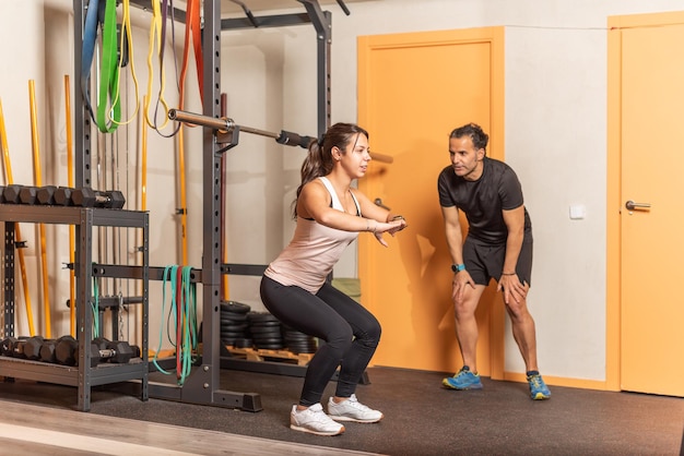 Desportista fazendo agachamento sem exercícios de ponderação com o treinador no ginásio. Conceito de ginásio.