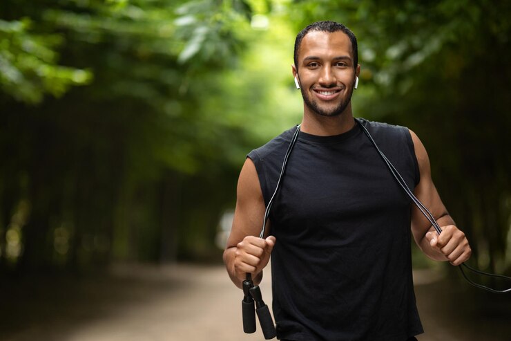 Foto desportista negro positivo se exercitando com pular corda no parque público