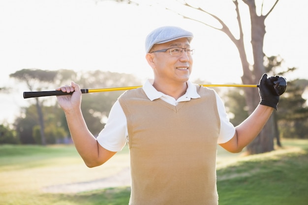 Desportista, olhando para longe com seu taco de golfe