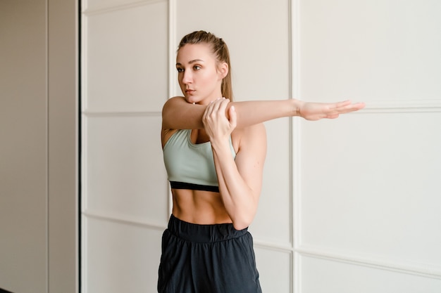 Desportiva jovem alongamento e fazendo exercício em casa