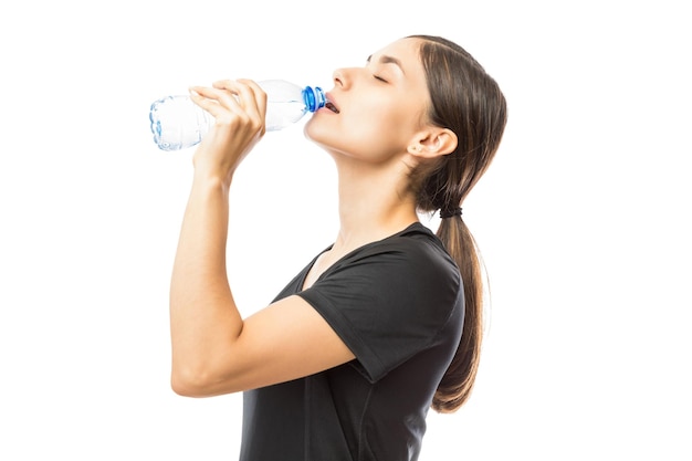 Desportiva jovem bebendo água da garrafa após treino sobre fundo branco