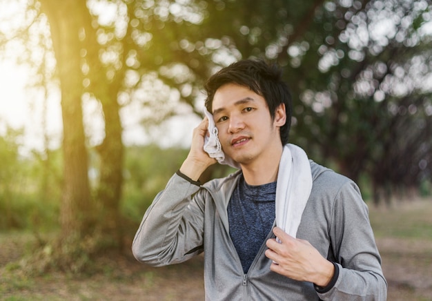 desportivo homem descansando e limpando o suor com uma toalha depois de exercícios de esporte de treino ao ar livre