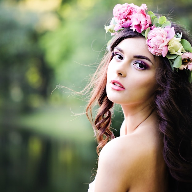 Despreocupada jovem moda mulher com cabelo encaracolado ventoso ao ar livre. Menina da moda em fundo verde