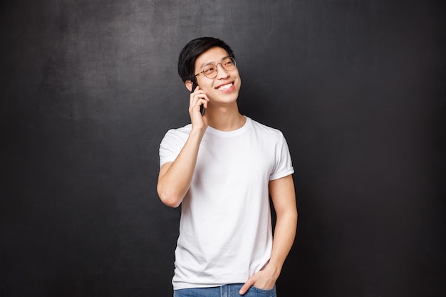 Despreocupado alegre homem asiático falando no telefone com atitude amigável