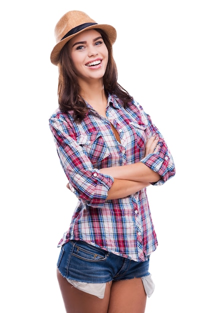 Despreocupado e positivo. Mulher jovem e bonita com roupa descolada, de braços cruzados e olhando para a câmera em pé contra um fundo branco