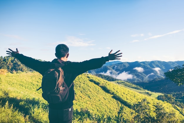 Despreocupado, homem feliz, desfrutando da natureza em cima do penhasco da montanha com o nascer do sol. Conceito de liberdade