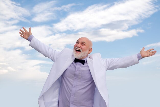 Despreocupado oldfashion ganador senior viejo hombre maduro vintage éxito masculino en traje blanco divirtiéndose