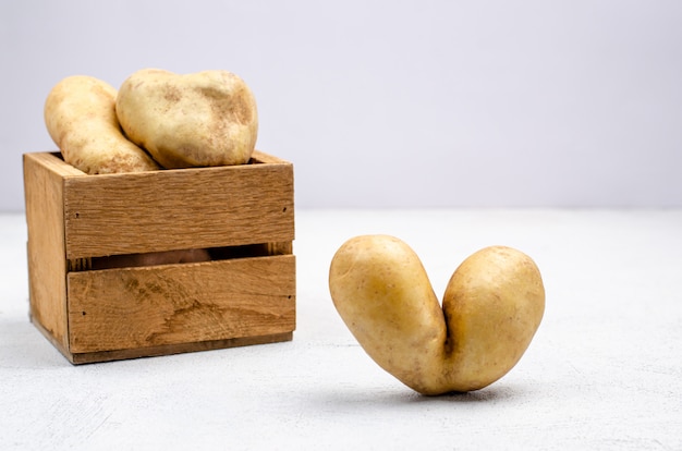 Desprezíveis batatas de diferentes formas em uma caixa de madeira, copie o espaço.