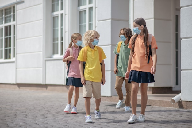 Después del colegio. Grupo de escolares con máscaras protectoras en su camino a casa después de las lecciones