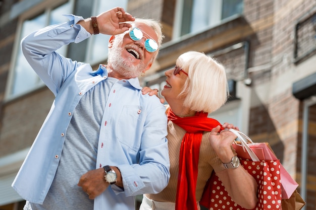 Después de las compras. Cintura para arriba de la adorable pareja de ancianos con estilo disfrutando de un paseo juntos mientras sostienen paquetes con compras compradas recientemente