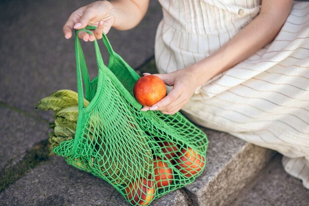 Después de las compras. Mujer joven sentada en los escalones con una bolsa de frutas