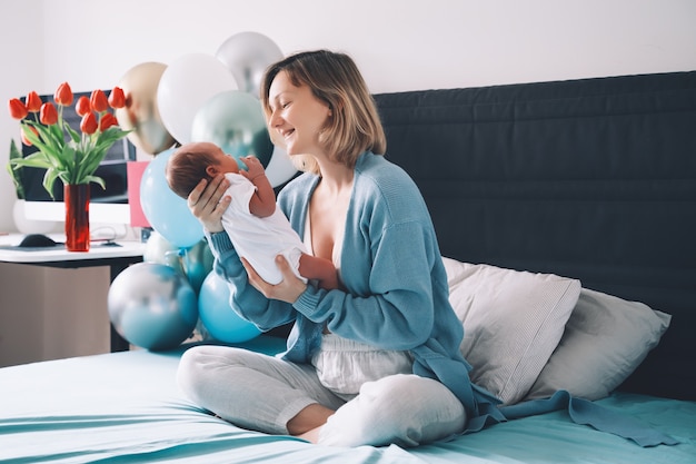 después del parto, la madre y el bebé en casa, la madre sostiene al recién nacido en manos de la madre y el bebé juntos