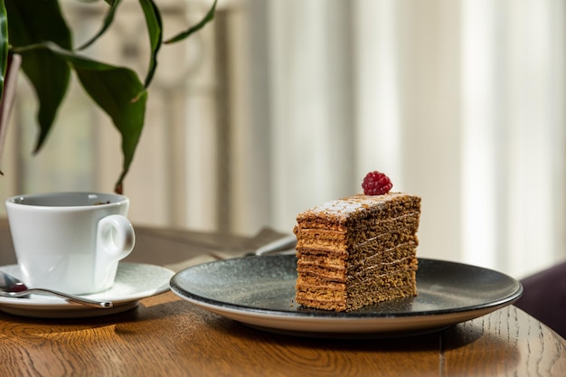 Dessert dekoriert mit Himbeeren, serviert mit Kaffee. Foto des Desserts im Innenraum