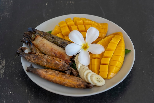 Dessert im thailändischen Stil gelbe Mango mit klebrigem Bananenreis in Palmblättern Gelbe Mango und klebriger Reis ist ein beliebtes traditionelles Essen in Thailand Nahaufnahme